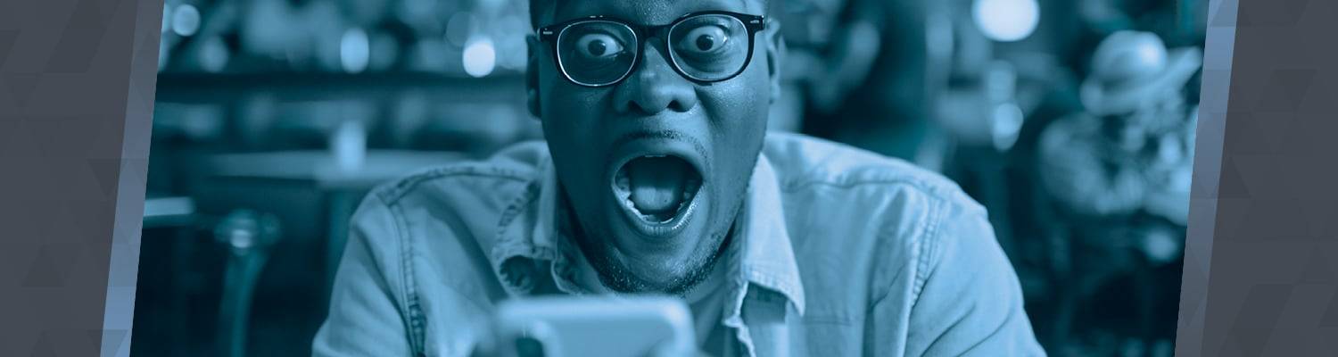 Person with glasses looking at their phone in surprise.