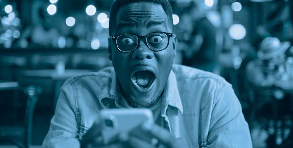 Person with glasses looking at their phone in surprise.